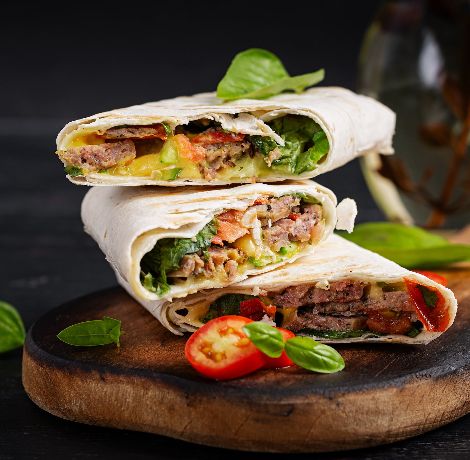 Grilled tortilla wraps with beef and fresh vegetables on wooden board. Beef burrito. Mexican food. Healthy food concept.